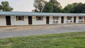 A motel with a row of rooms, each with a door and a window. There is a grassy area in front of the building. - Motel at KY Lake. Reel & Relax (Gilbertsville)