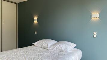 A bedroom with a bed, two wall-mounted light fixtures, and a door.
