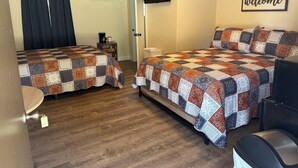 A room with two beds, a TV, a welcome sign, and a coffee maker.