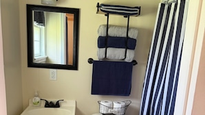 A bathroom with a white sink, a toilet, a mirror, and a striped shower curtain.