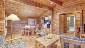 Interior de uma cabana de madeira com sala de jantar, cozinha e área de estar.