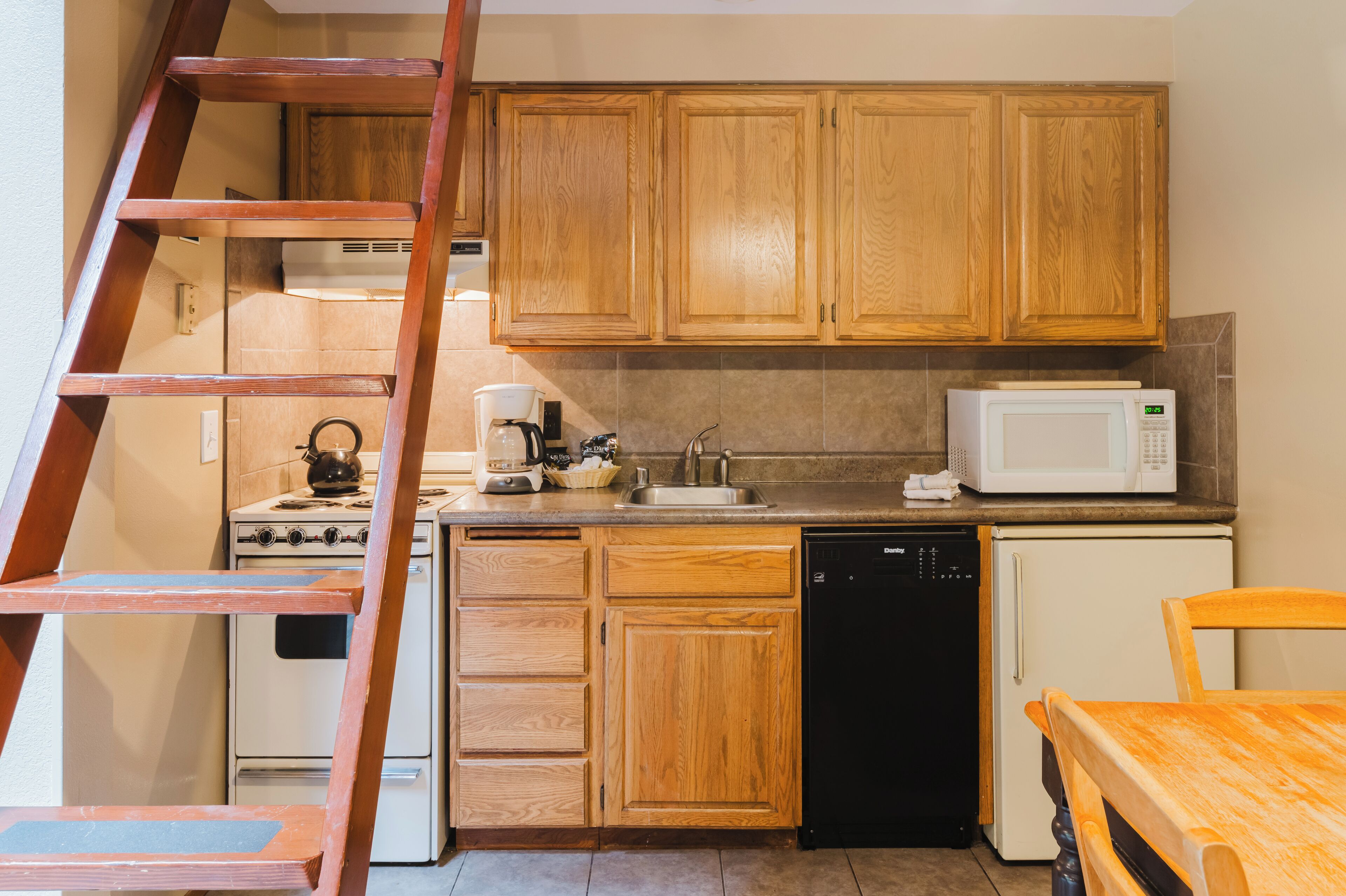 A kitchen with wooden cabinets, a stove, a microwave, a sink, and a dishwasher.