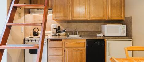 A kitchen with wooden cabinets, a stove, a microwave, a sink, and a dishwasher.