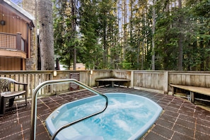 Relax in the hot tub surrounded by serene forest views.