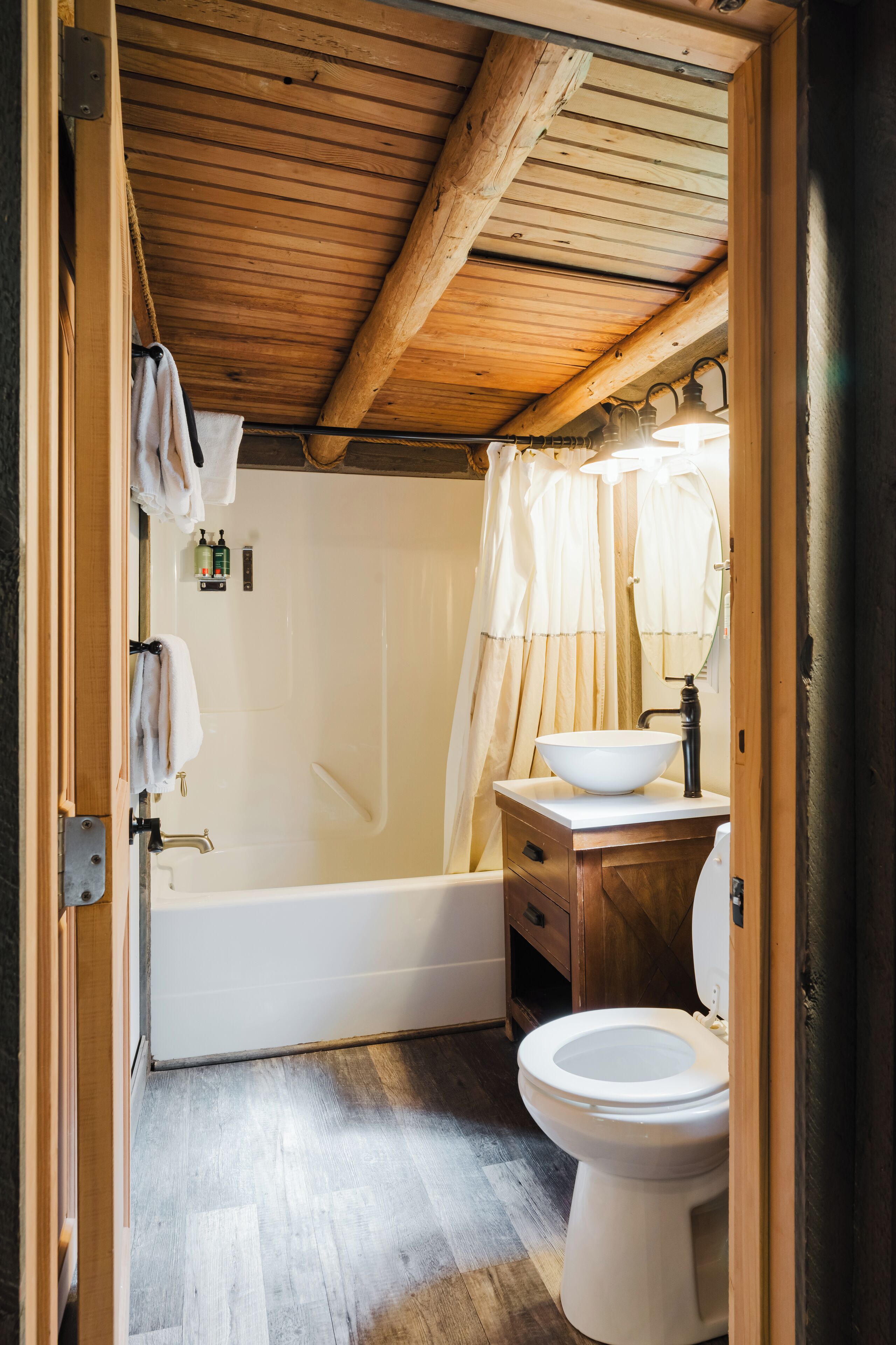 Een houten plafond, een badkuip, een wastafel en een toilet in een badkamer.