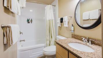 A bathroom with a bathtub, toilet, sink, and a mirror.