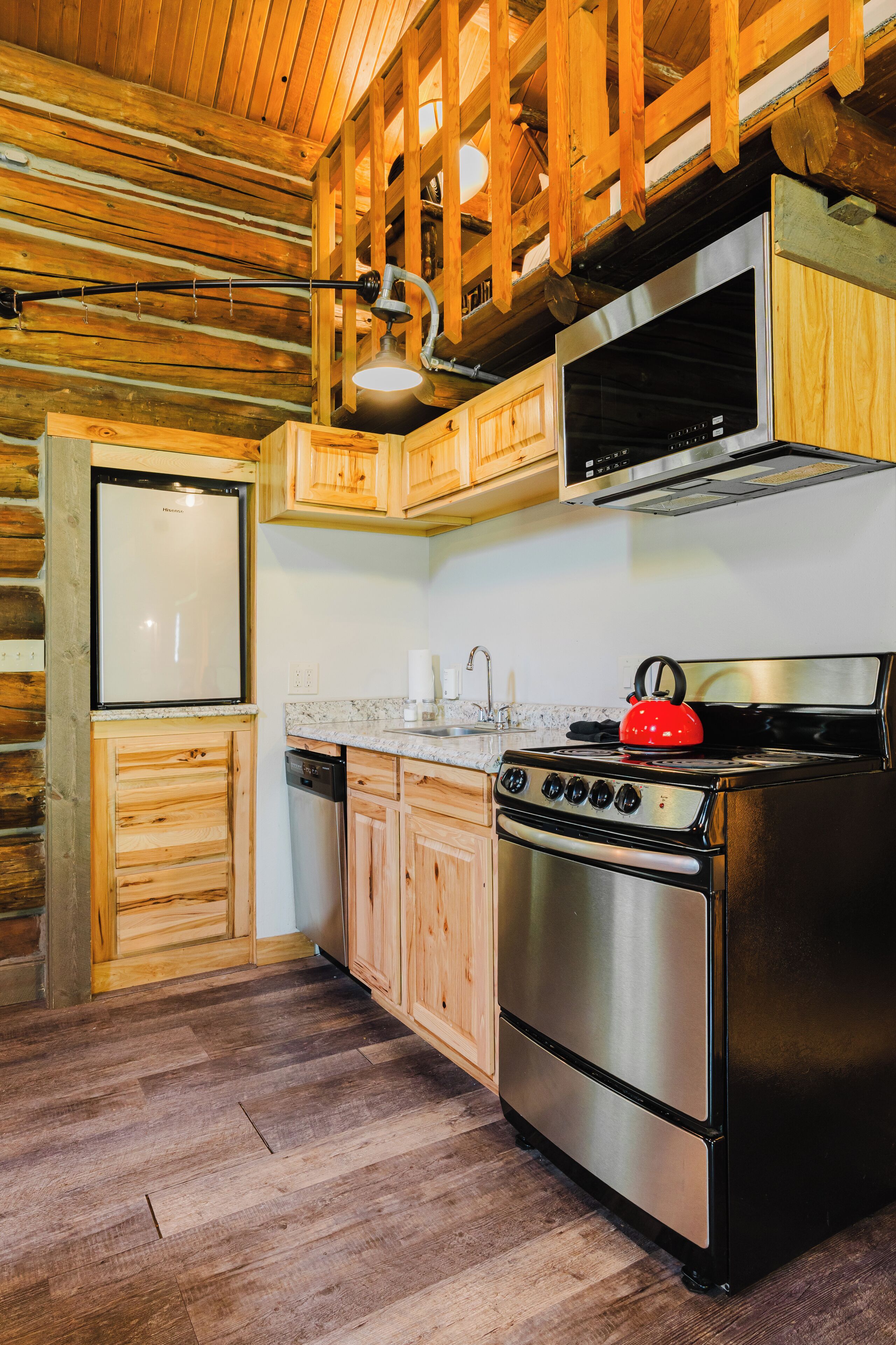 A kitchen with wooden cabinets, a stainless steel refrigerator, a stove, and a microwave.