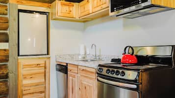 A kitchen with wooden cabinets, a stainless steel refrigerator, a stove, and a microwave.