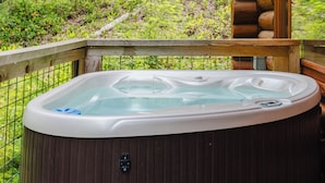 Ein Whirlpool auf einer Holzterrasse mit Blick auf ein bewaldetes Gebiet.