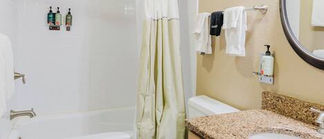 A bathroom with a bathtub, toilet, sink, and a shower curtain.
