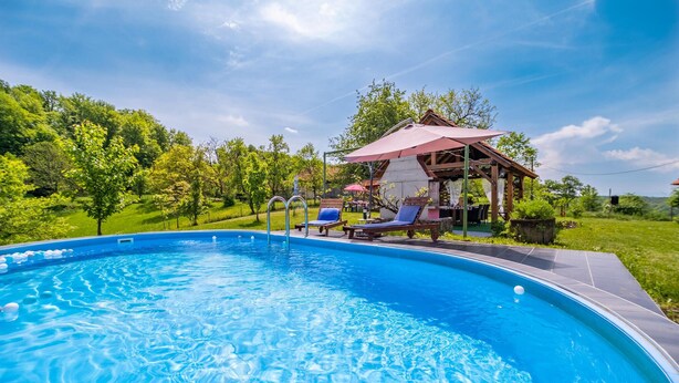 Ein Schwimmbecken mit Holzterrasse und Liegestühlen.
