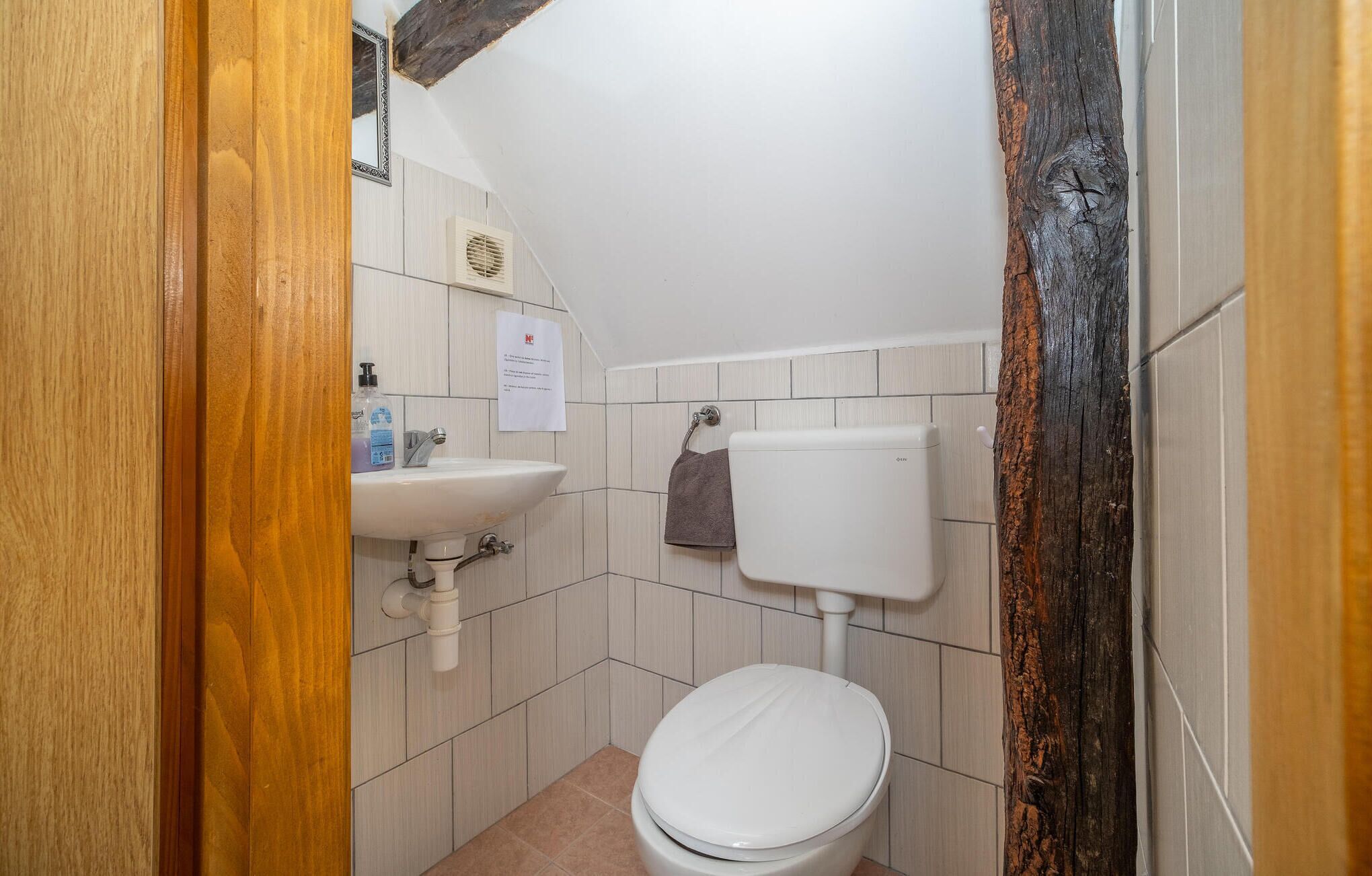 A small bathroom with a white toilet, a sink, and a towel hanging on the wall.