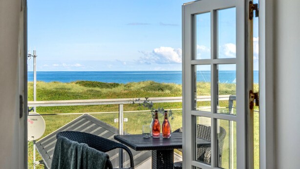 A balcony with a table, two bottles, and a view of the ocean. - Amazing home in Frøstrup with sauna (Frøstrup)
