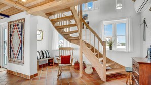 A spacious room with a wooden staircase, a large window with a view, and a cozy seating area with a patterned rug and cushions. - Amazing home in Frøstrup with sauna (Frøstrup)