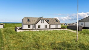 A two-story house with a sloped roof, a small attached garage, and a flagpole in front. - Amazing home in Frøstrup with sauna (Frøstrup)