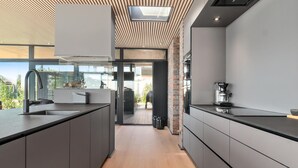 A modern kitchen with dark cabinetry, a large island, and a coffee machine. - Awesome home in Knebel with sauna (Knebel)