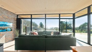A modern living room with a green sofa, large windows, and a wooden ceiling. - Awesome home in Knebel with sauna (Knebel)