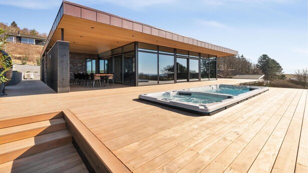 A modern house with a wooden deck, a hot tub, and a dining area with outdoor seating. - Awesome home in Knebel with sauna (Knebel)