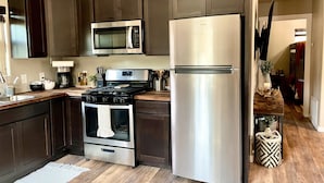Una cucina moderna con mobili scuri, elettrodomestici in acciaio inossidabile e un piano di lavoro in legno.