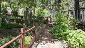 A stone pathway with wooden railings, surrounded by lush greenery and trees.