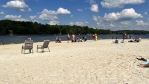 Ein Strand mit Sand, ein See und ein Wald im Hintergrund.