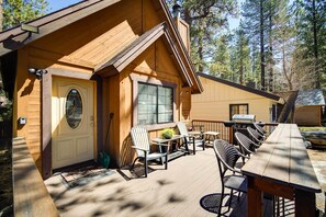 Een houten hut met terras, zitplaatsen buiten en een barbecue.