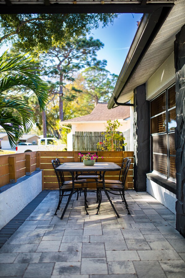 Une terrasse extérieure avec une table et des chaises en bois, un pot de fleurs et une vue sur le quartier.
