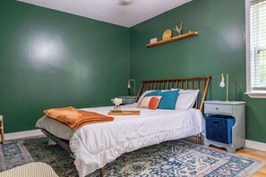 Une chambre à coucher avec un lit, une table de chevet et une fenêtre avec des stores.