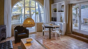 A cozy living room with a fireplace, a dining table with chairs, and a large window with curtains.