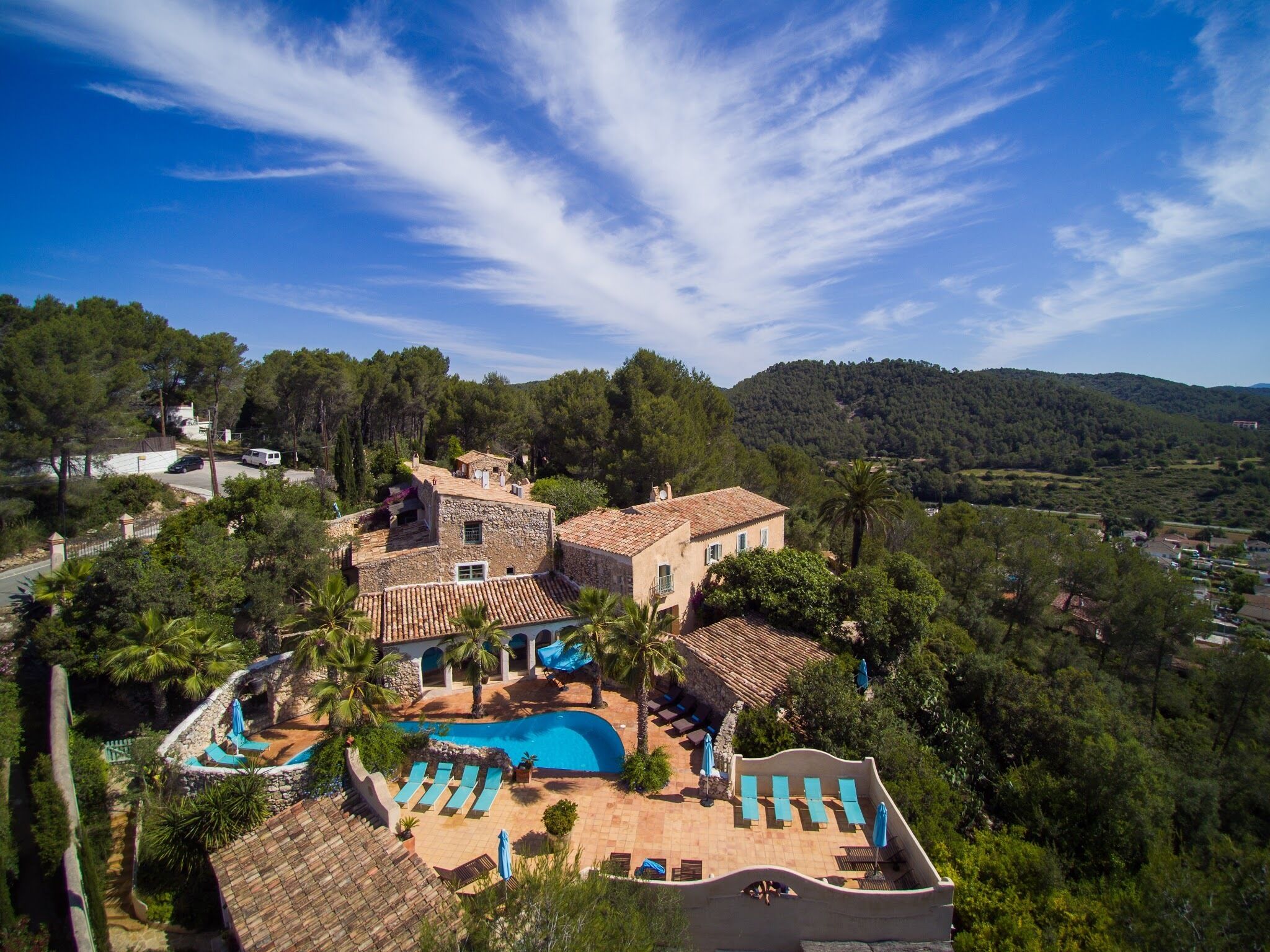 A villa with a swimming pool, outdoor seating, and a view of the surrounding landscape.
