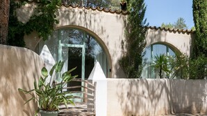 A building with arched doorways, a concrete wall, and a potted plant.