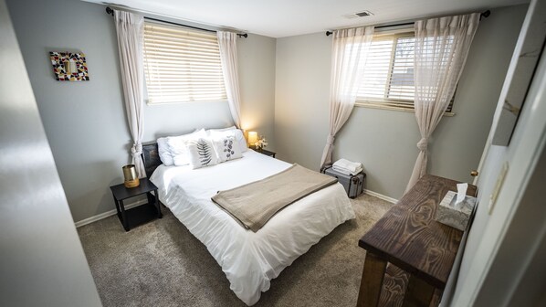 A neatly arranged bedroom with a bed, bedside tables, a lamp, and a suitcase.