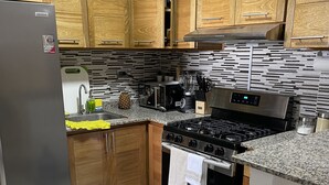 Een moderne keuken met houten kastjes, een roestvrijstalen koelkast, een gasfornuis en een inbouwoven.