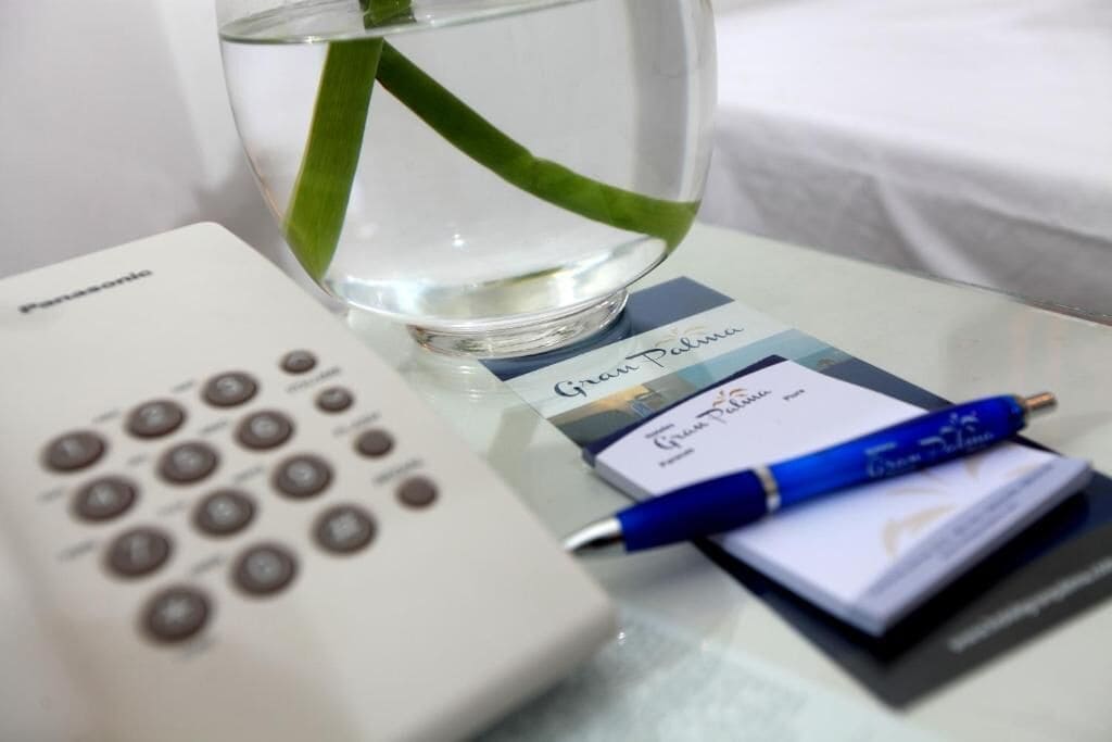 A Panasonic remote control, a glass of water with a green leaf, a blue pen, and a card on a table.