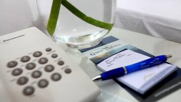 A Panasonic remote control, a glass of water with a green leaf, a blue pen, and a card on a table.