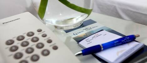 A Panasonic remote control, a glass of water with a green leaf, a blue pen, and a card on a table.