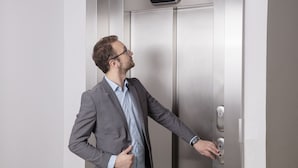 Un hombre con traje abre la puerta de un ascensor.