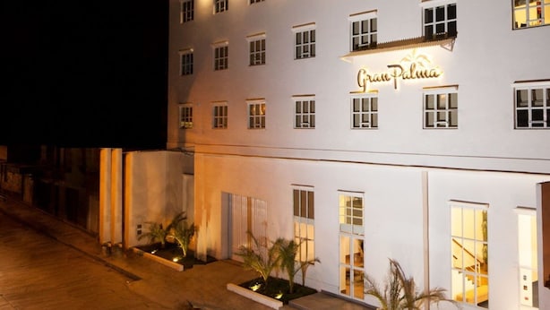 Un hotel de varios pisos con fachada blanca, ventanas iluminadas y un cartel que dice 'Gran Paloma'.