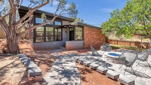 Una casa moderna con amplios ventanales, fachada de piedra y un patio con mobiliario exterior.