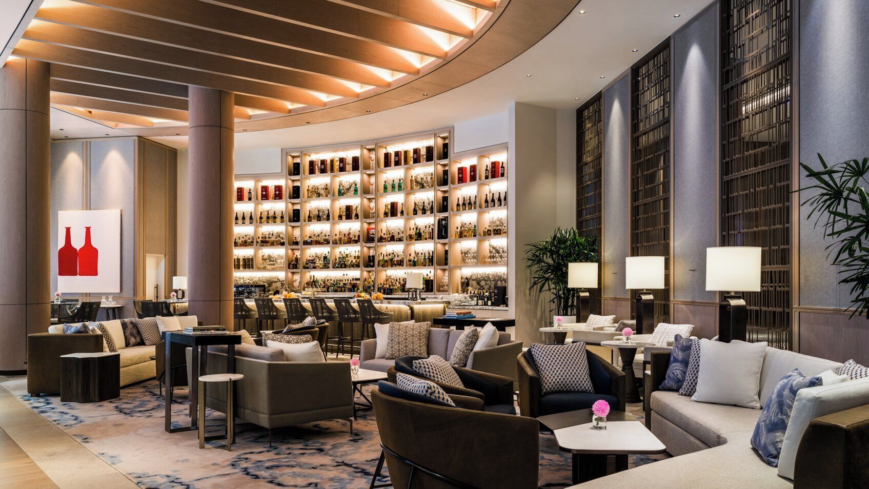 A spacious lobby with a bar area, seating arrangements, and a large wine display.