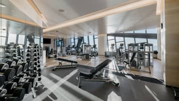 A modern gym with various exercise equipment, large windows, and a clean, spacious layout.