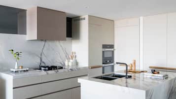 Una cocina moderna con encimera de mármol, horno empotrado y un lavabo con barra de madera.