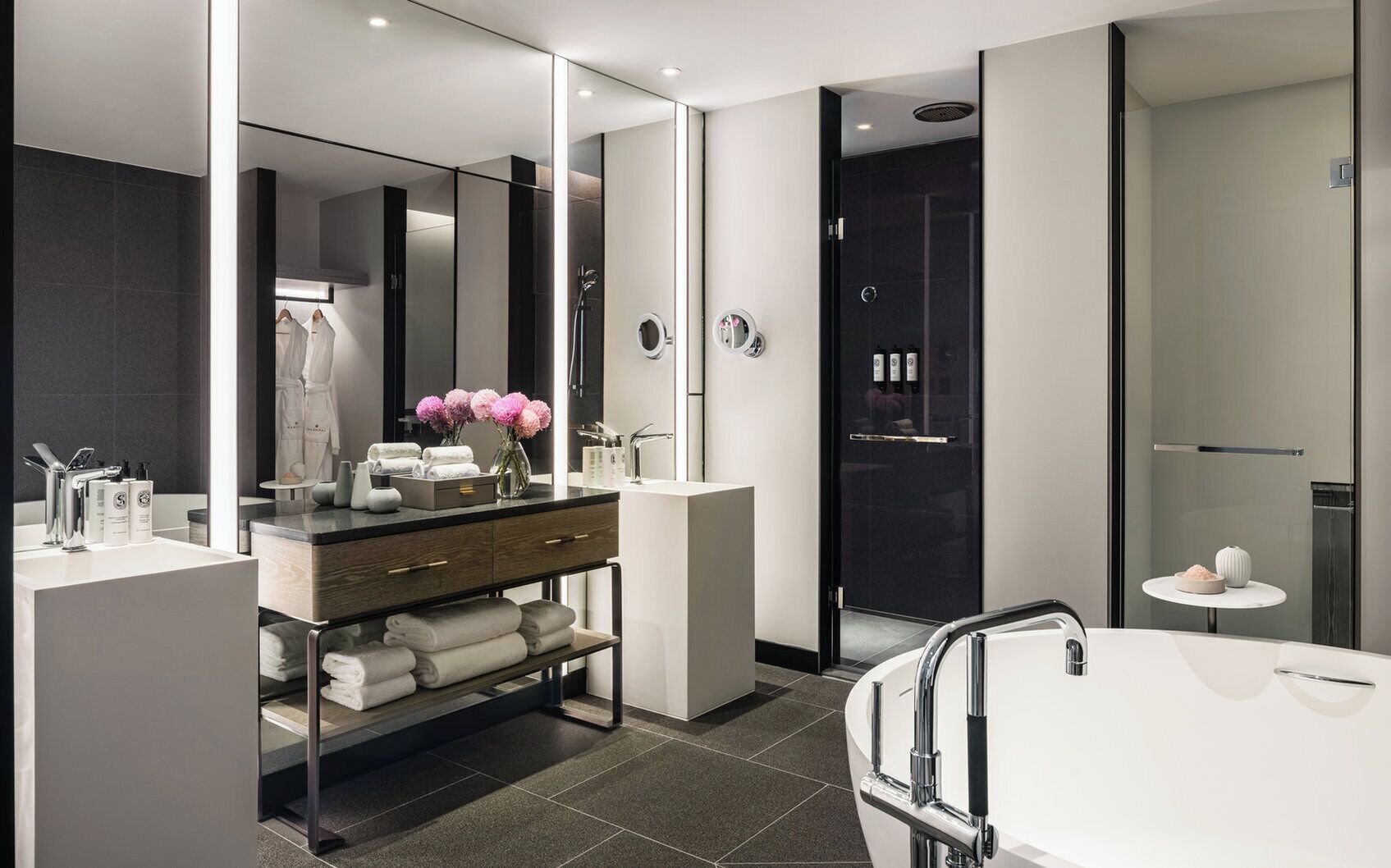 A modern bathroom with a large mirror, a vanity with a sink, a bathtub, and a shower area.