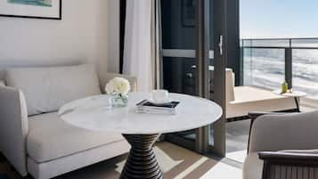 A modern living room with a round marble table, a sofa, and a balcony with a view of the sea.