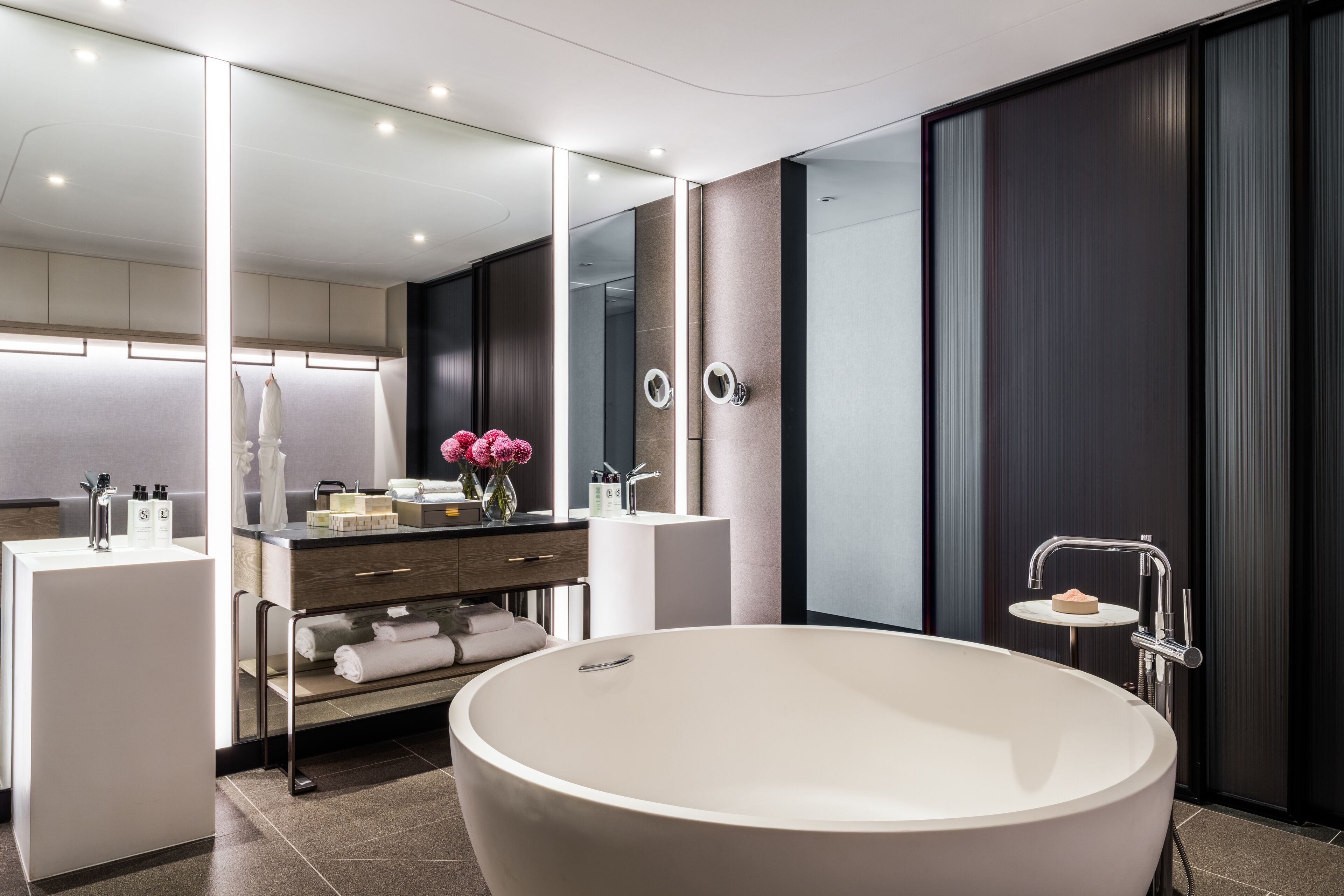 Un bagno moderno con una grande vasca da bagno freestanding, un mobile lavabo con specchio e un piccolo lavandino.