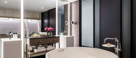 A modern bathroom with a large freestanding bathtub, a vanity with a mirror, and a small sink.