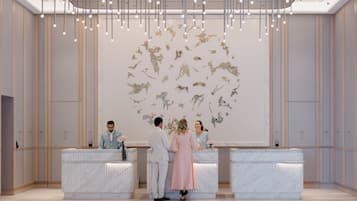 A reception area with marble counters, a modern chandelier, and a wall art installation.