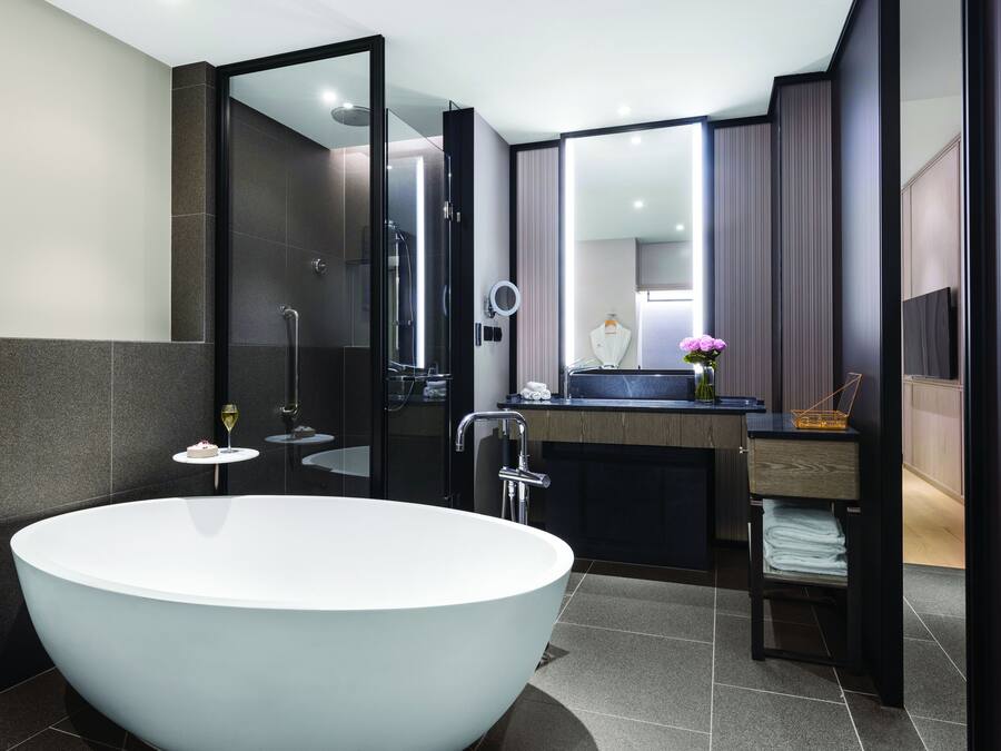 A modern bathroom with a large freestanding bathtub, a vanity with a mirror, and a shower area.