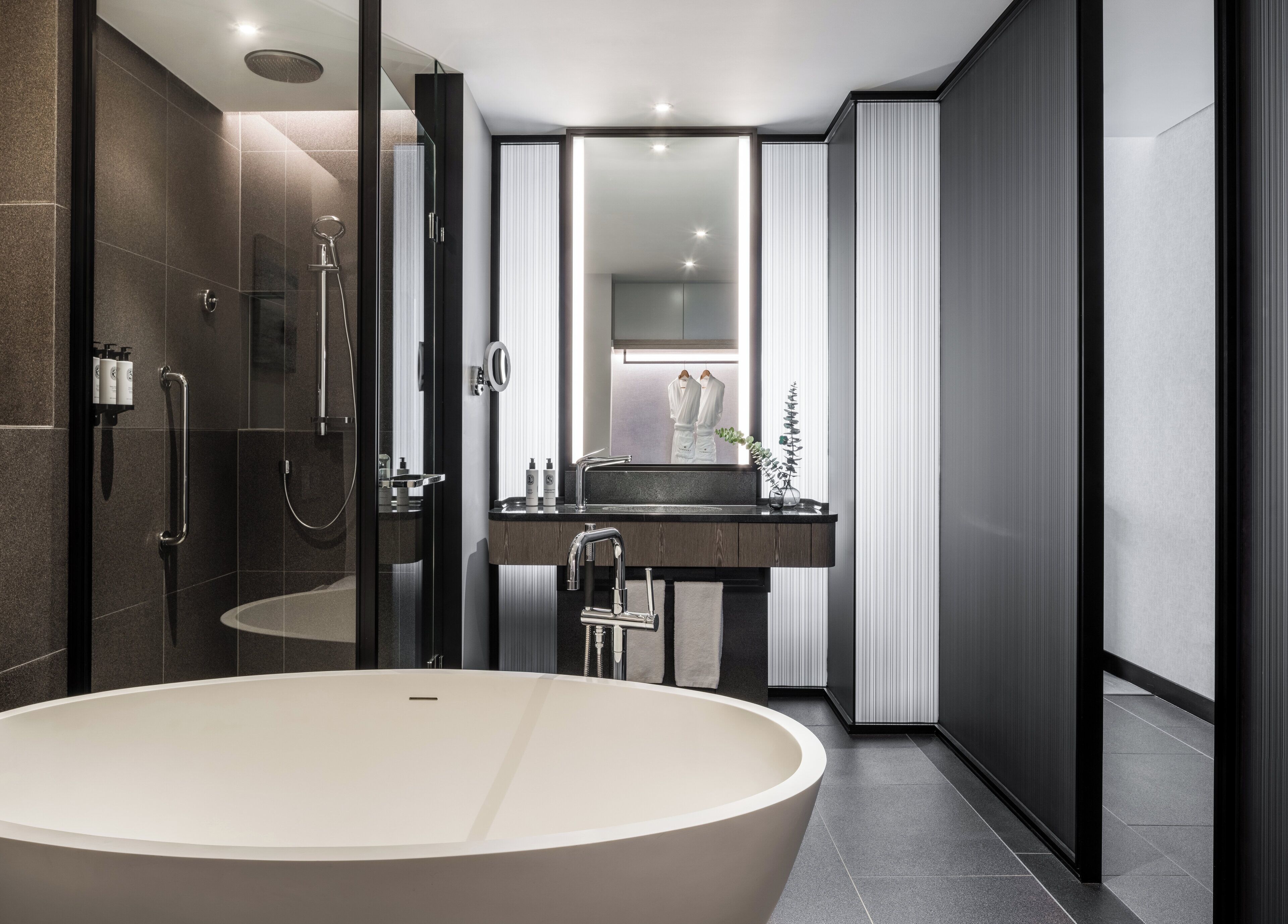 Un baño moderno con una bañera independiente, una ducha con cerramiento de vidrio y un tocador con espejo.