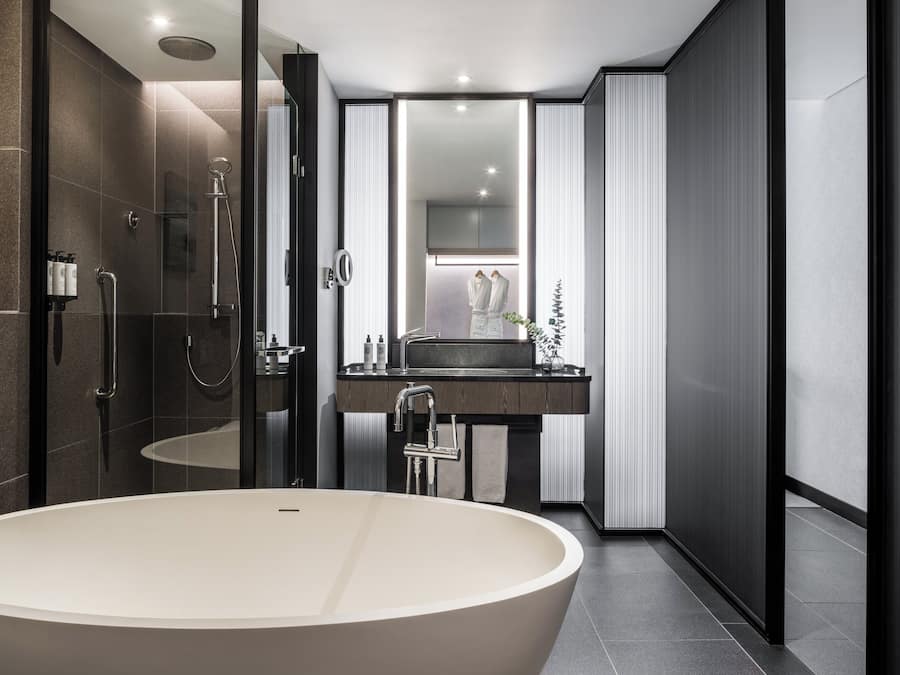 A modern bathroom with a freestanding bathtub, a glass-enclosed shower, and a vanity with a mirror.